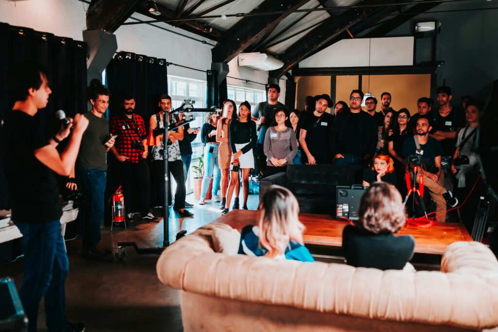 Speaker with microphone talking to casual audience, mostly standing.
public domain Matheus Bertelli