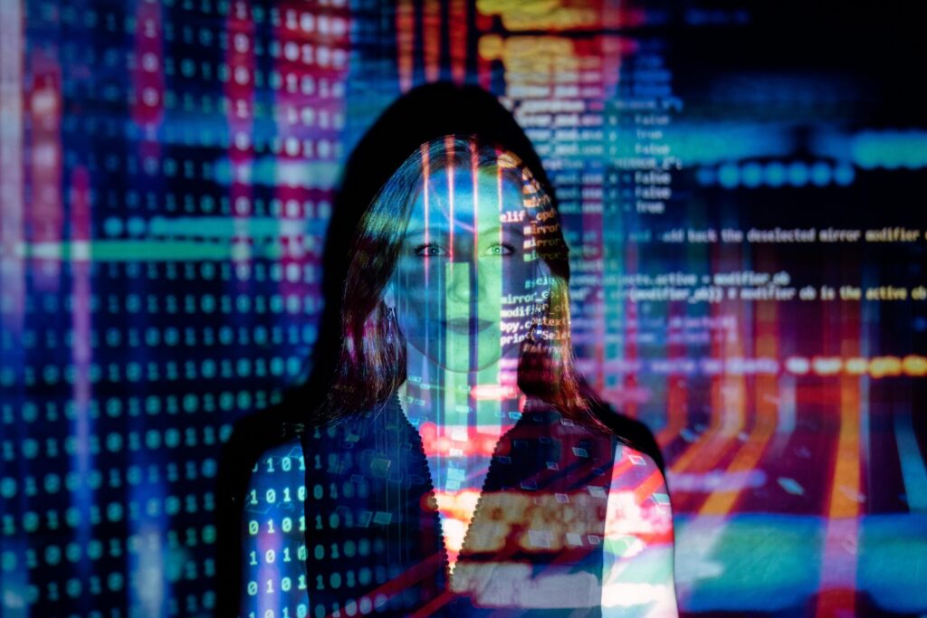 Woman standing with projector projecting computer code over her face.
public domain thisisengineering